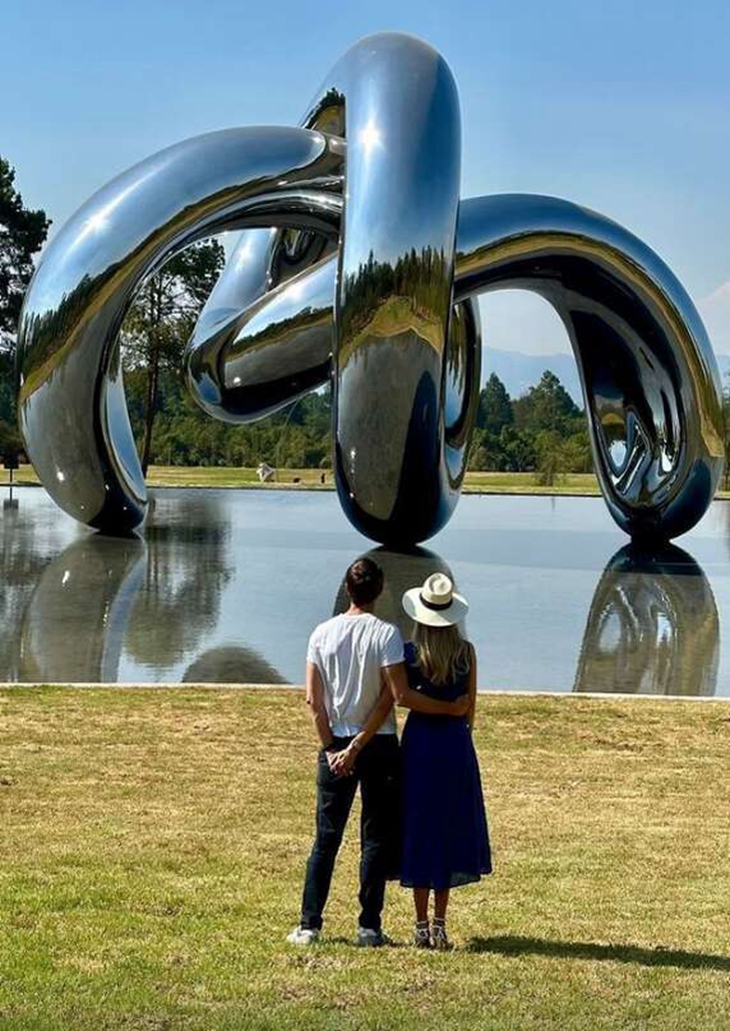 A Lovely Couple Enjoying the Large Mirror Polished Steel Crab Sculpture